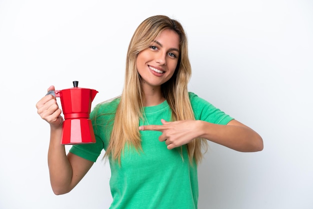 Jovem uruguaia segurando a cafeteira isolada no fundo branco e apontando para ela