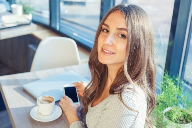 Foto jovem usa um laptop e celular em um café