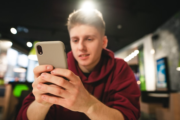 Jovem usa um smartphone em um café de fast food