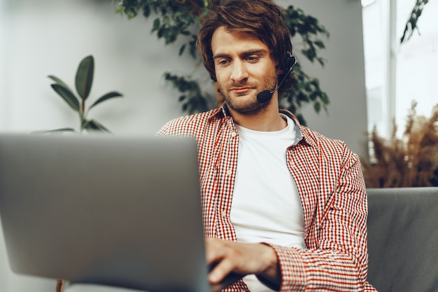 Jovem usando fone de ouvido fazendo uma videochamada com um laptop