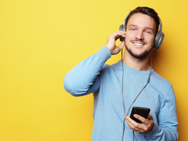 Jovem usando fones de ouvido e segurando o telefone móvel