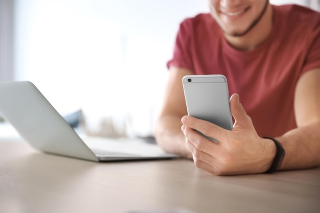 Jovem usando laptop e celular em casa