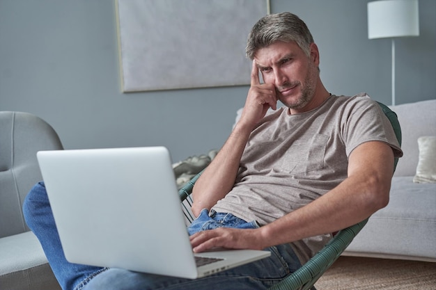 Jovem usando laptop e sorrindo em casa