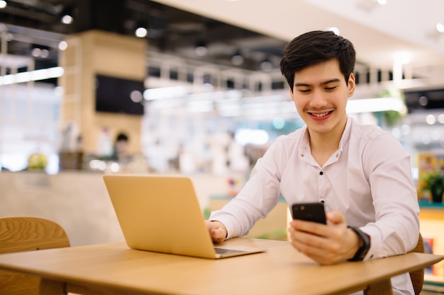 Jovem usando laptop e telefone inteligente na mesa ao ar livre