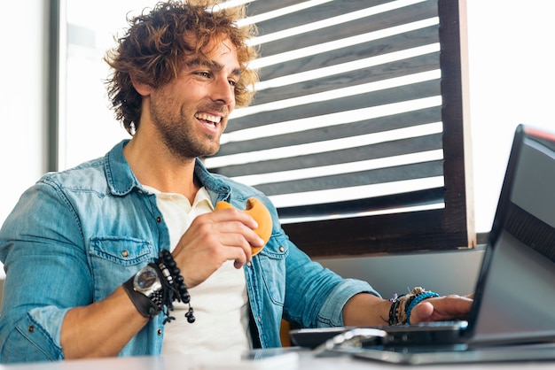 Jovem usando laptop enquanto almoça.