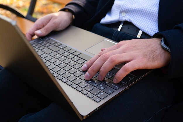 Jovem usando laptop no parque de outono Closeup Businessman em laptop