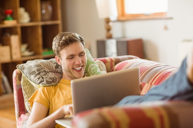 Jovem usando laptop no sofá