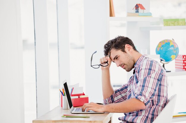 Jovem, usando o laptop em sua mesa