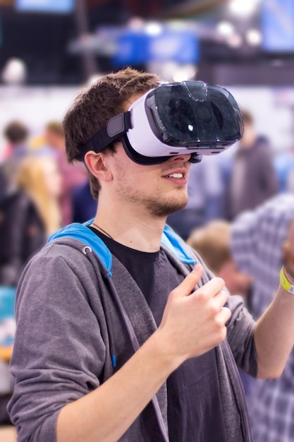 Jovem usando óculos de realidade virtual em uma exposição está se divertindo