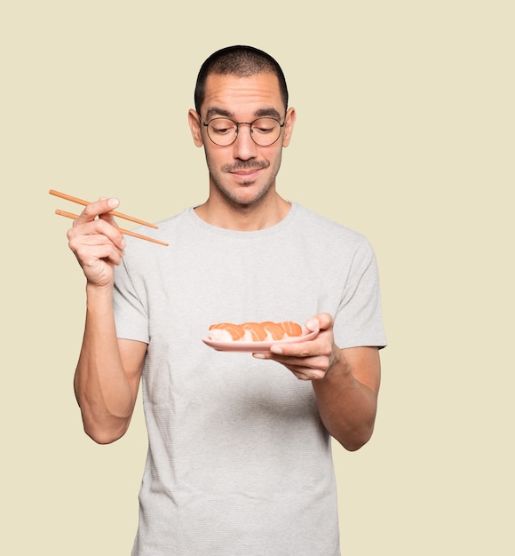 Jovem usando pauzinhos para comer sushi