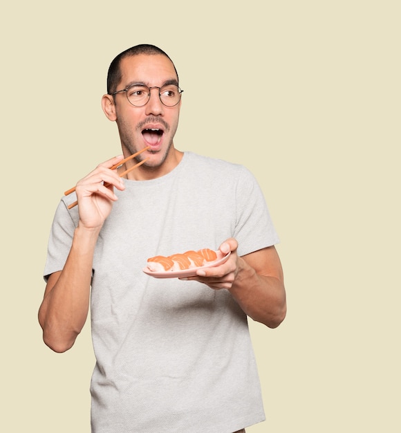 Jovem usando pauzinhos para comer sushi