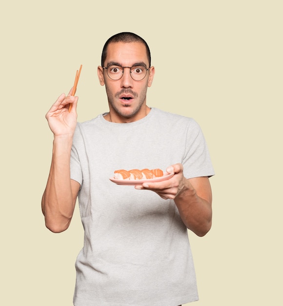 Jovem usando pauzinhos para comer sushi