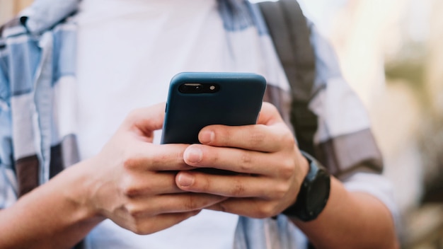 Jovem, usando seu telefone celular na cidade. Close-up de um homem usando telefone móvel esperto