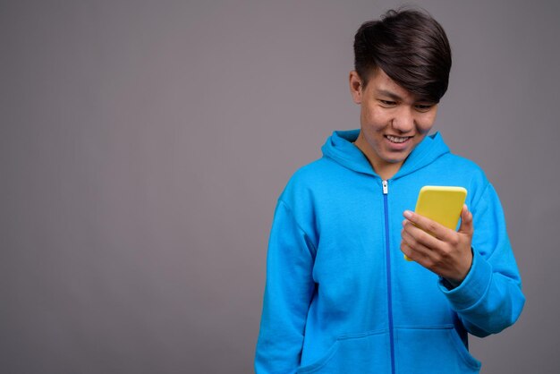 Jovem usando smartphone contra um fundo cinzento