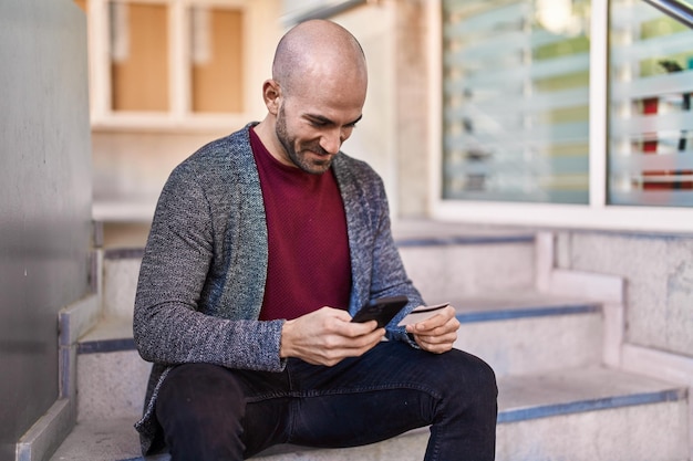 Jovem usando smartphone e cartão de crédito na rua