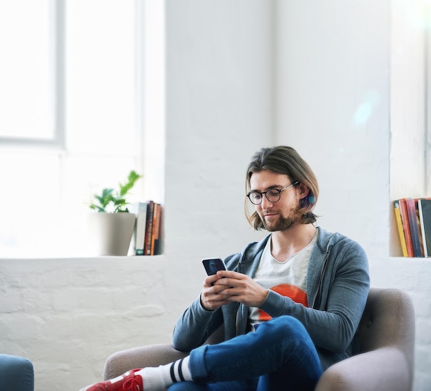 Jovem usando smartphone em casa enviando mensagens de texto lendo mensagens de mídia social navegando online