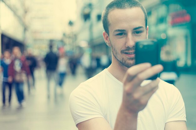 Foto jovem usando smartphone enquanto está de pé na rua da cidade