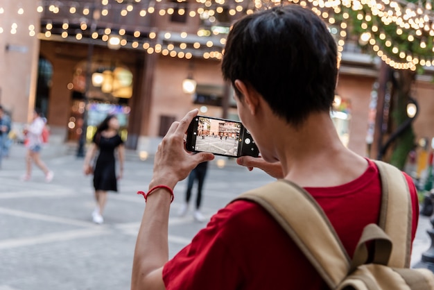 Jovem usando smartphone móvel tirar uma foto por aplicativo de câmera.