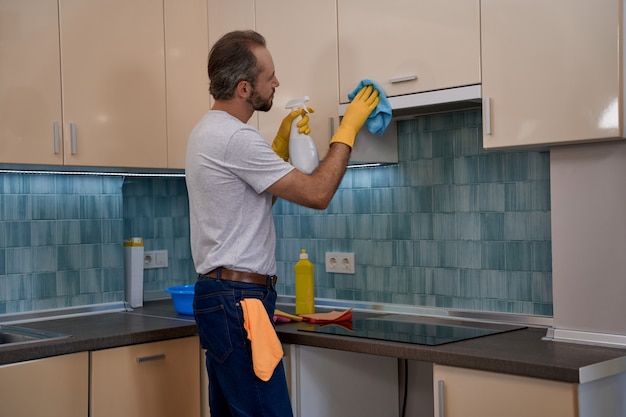 Jovem usando spray de detergente e pano na mobília