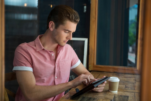 Jovem usando tablet digital na mesa de um café