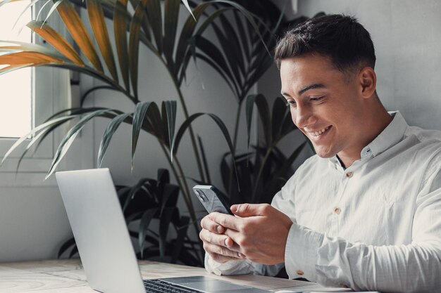 Foto jovem usando telefone celular enquanto está sentado na mesa