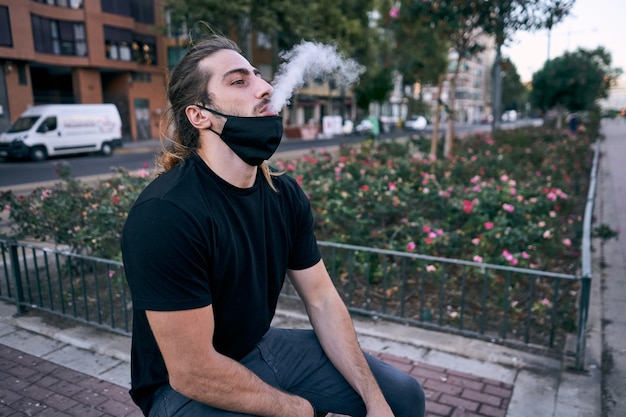 Jovem usando um cigarro eletrônico na rua