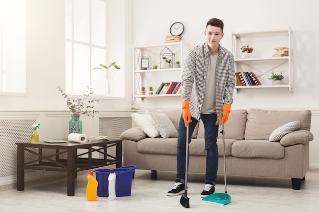 Jovem varrendo uma casa. Conceito de arrumação, limpeza de primavera e arrumação, espaço de cópia