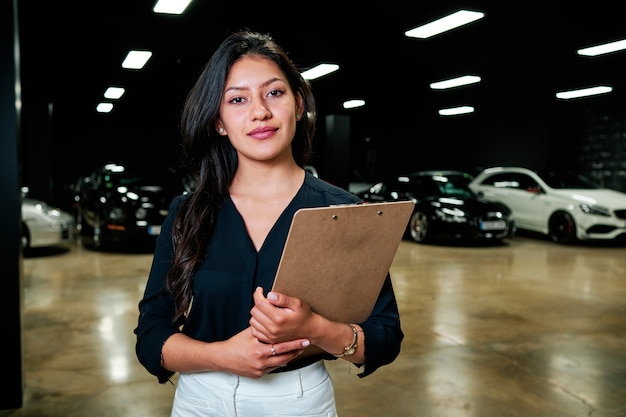 Jovem vendedora latina vendendo carros de luxo