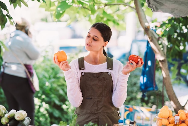 Jovem vendedora segurando tomates caseiros nas mãos