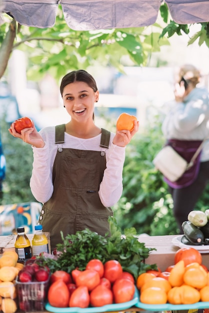 Jovem vendedora segurando tomates caseiros nas mãos