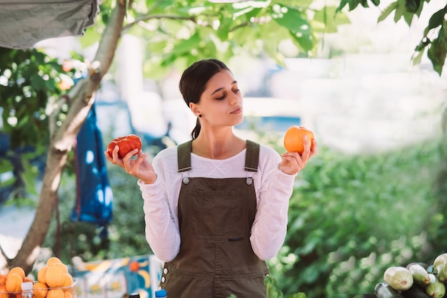 Jovem vendedora segurando tomates caseiros nas mãos