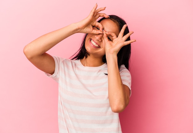 Jovem venezuelana isolada em um fundo rosa mostrando sinal de aprovação sobre os olhos