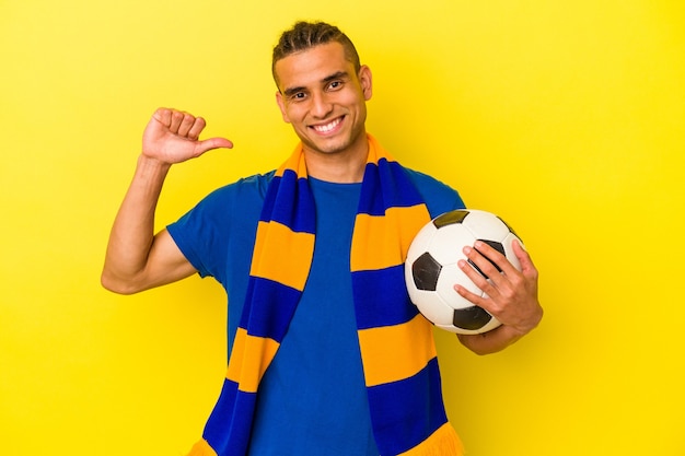 Jovem venezuelano assistindo futebol isolado em fundo amarelo sente-se orgulhoso e autoconfiante, exemplo a seguir.