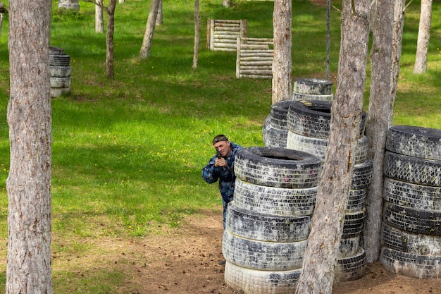 Jovem vestido em camuflagem jogando laser tag no playground especial da floresta