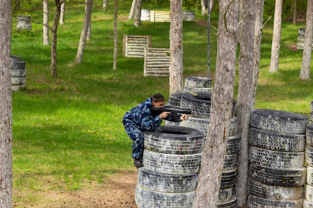 Jovem vestido em camuflagem jogando laser tag no playground especial da floresta