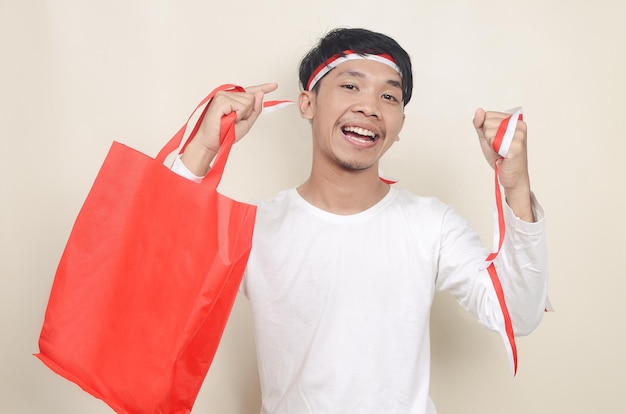 Jovem vestindo fita na cabeça segurando sacolas de compras em fundo isolado conceito de desconto do dia da independência