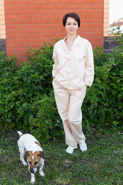 Jovem vestindo pijama com seu cachorro no quintal O conceito de animais e amizade ou dono de animais e amor