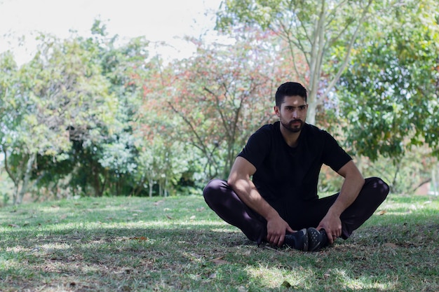 jovem vestindo roupas atléticas sentado no parque praticando ioga