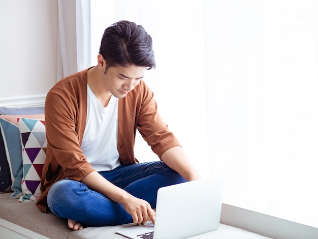 Jovem vestindo roupas casuais e usando laptop