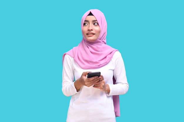 jovem vestindo um hijab rosa segurando o telefone, olhando para longe, modelo indiano do paquistanês