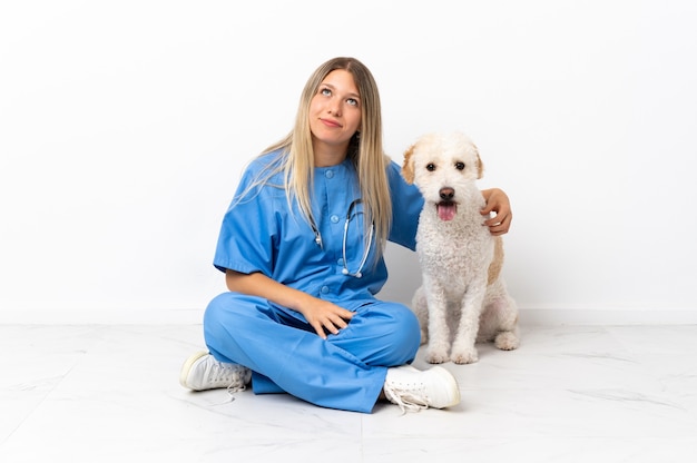 Jovem veterinária com o cachorro sentado no chão olhando para cima