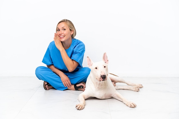 Jovem veterinária inglesa sentada no chão com um cachorro sussurrando algo