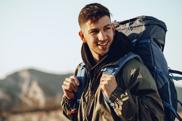 Jovem viajante com mochila grande, caminhando nas montanhas