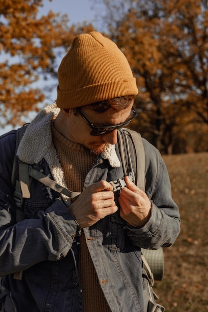 Foto jovem viajante masculino curvando mochila de caminhada na floresta de outono