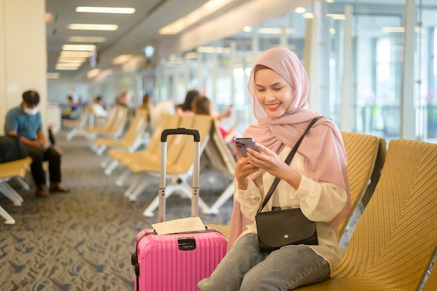 Jovem viajante muçulmana carregando malas no aeroporto internacional