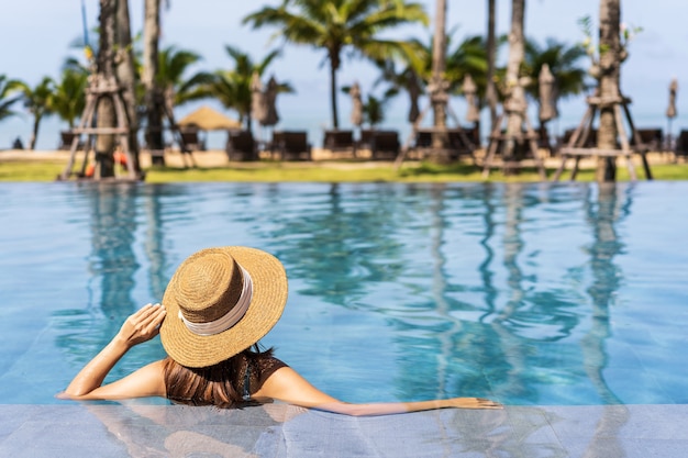 Jovem viajante relaxando e se divertindo à beira da piscina de um resort tropical enquanto viaja nas férias de verão, conceito de viagens