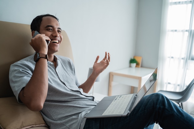 Jovem viajante usando laptop e falando por telefone