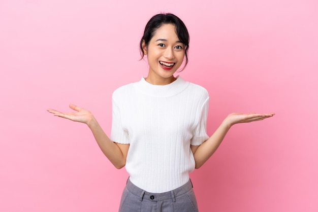 Jovem vietnamita isolada em fundo rosa com expressão facial chocada