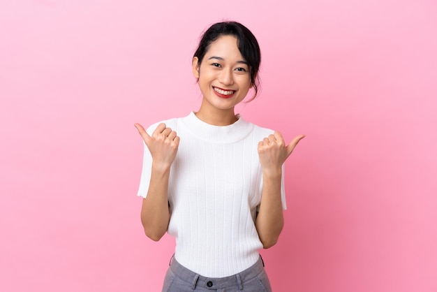 Jovem vietnamita isolada em fundo rosa com polegares para cima gesto e sorrindo