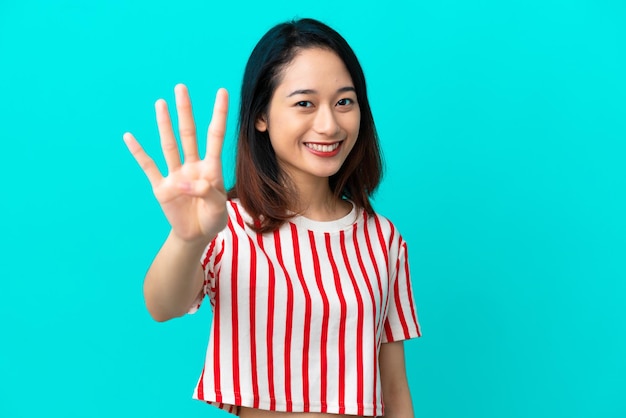 Jovem vietnamita isolada em um fundo azul feliz e contando quatro com os dedos